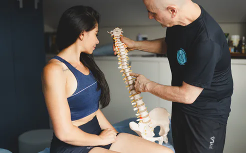 Fisioterapeuta explicando a coluna vertebral para uma paciente